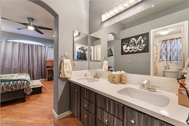 ensuite bathroom featuring a sink, connected bathroom, wood finished floors, and a ceiling fan