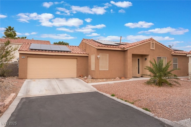 view of front of house with stucco siding, driveway, solar panels, and an attached garage