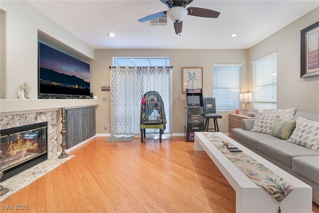 living area featuring wood finished floors, visible vents, baseboards, a fireplace, and recessed lighting