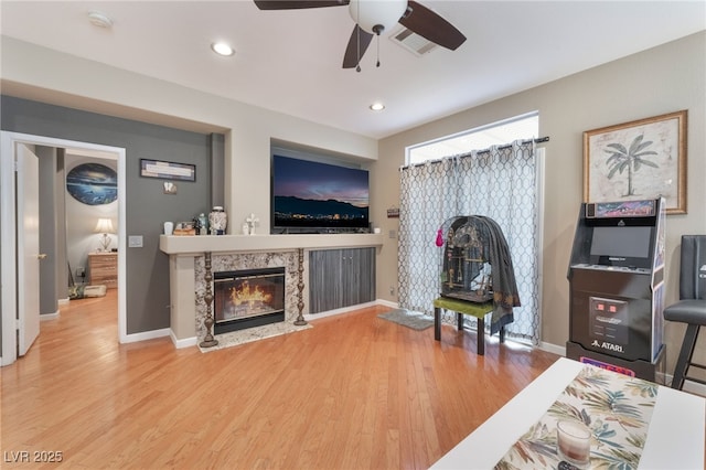 living area with wood finished floors, a fireplace, visible vents, and baseboards