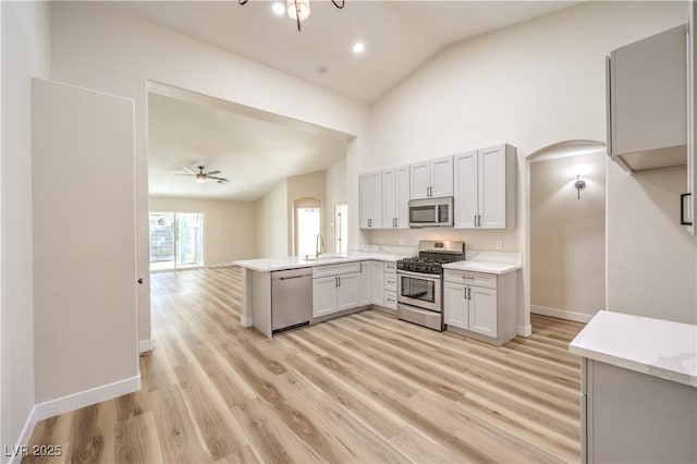 kitchen featuring light countertops, arched walkways, appliances with stainless steel finishes, and a sink