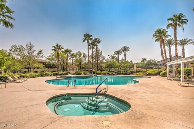 pool with a hot tub and a patio