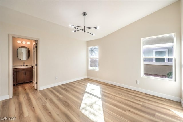 unfurnished dining area with baseboards, light wood-type flooring, an inviting chandelier, and vaulted ceiling