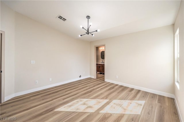 unfurnished room featuring a chandelier, visible vents, light wood-type flooring, and baseboards