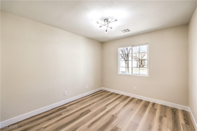 spare room with visible vents, baseboards, and light wood finished floors