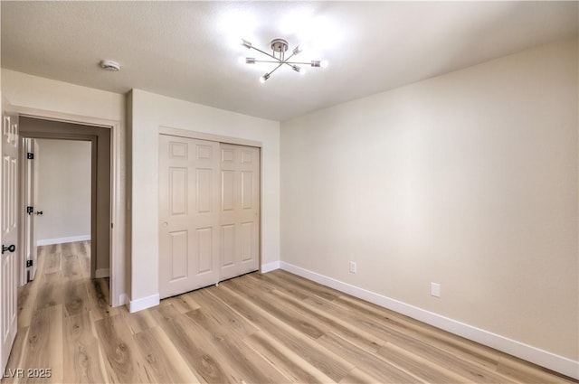 unfurnished bedroom with light wood-type flooring, baseboards, and a closet