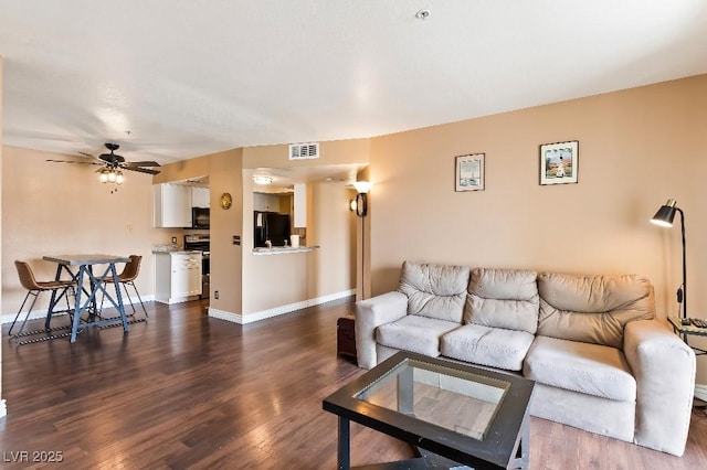 living area with a ceiling fan, dark wood-style floors, visible vents, and baseboards