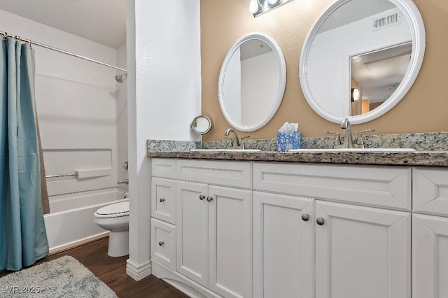 full bathroom with visible vents, double vanity, shower / bath combo, wood finished floors, and a sink