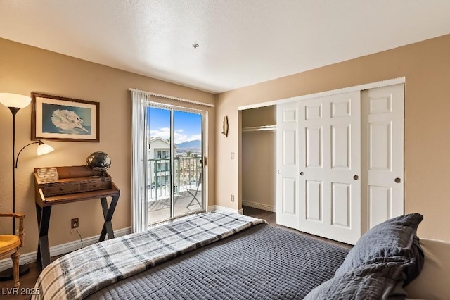 bedroom featuring wood finished floors, a closet, baseboards, and access to exterior