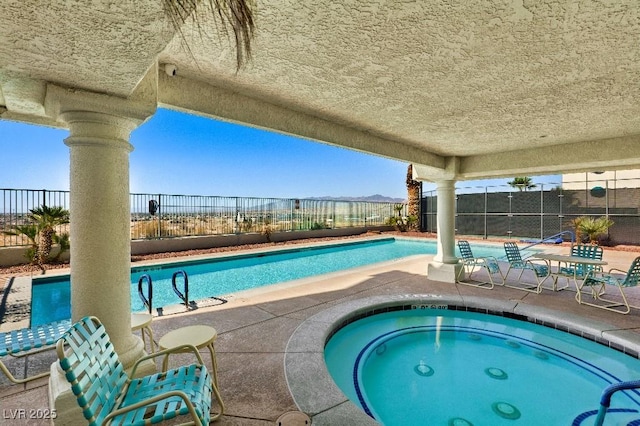 pool featuring a patio area, a community hot tub, and a fenced backyard