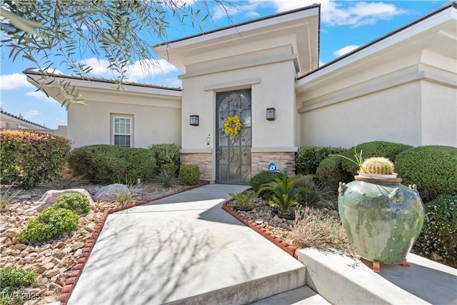 view of exterior entry with stone siding and stucco siding