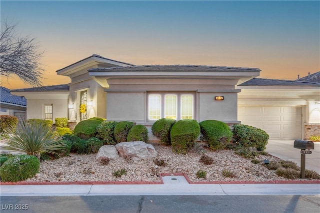 prairie-style house with stucco siding, concrete driveway, and an attached garage