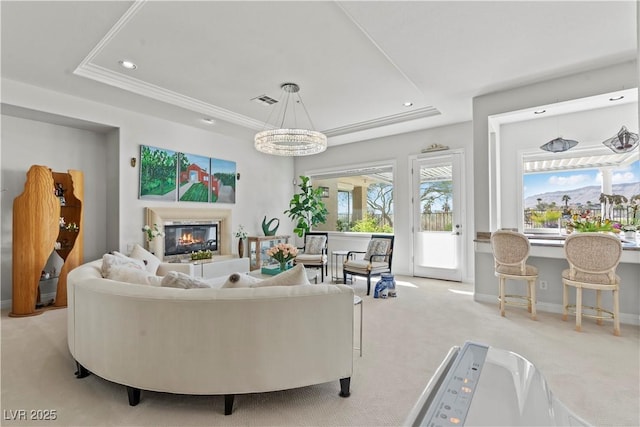 carpeted living area with visible vents, recessed lighting, a tray ceiling, and a glass covered fireplace