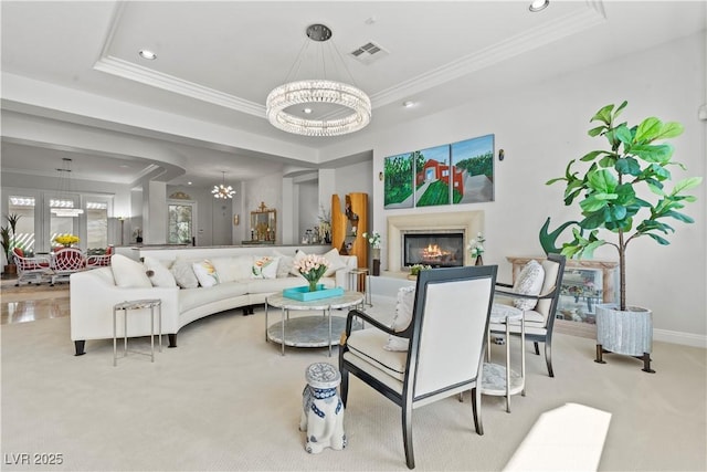 living area with visible vents, a raised ceiling, a chandelier, and ornamental molding