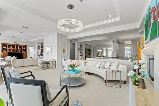 living room featuring a notable chandelier, plenty of natural light, a fireplace, and a raised ceiling