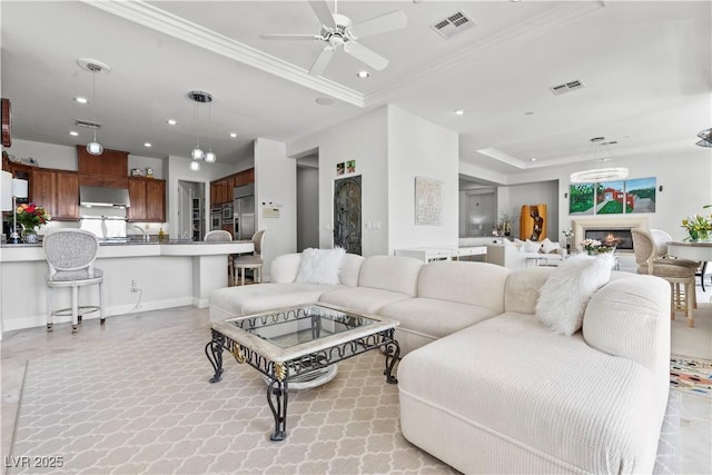 living area with recessed lighting, visible vents, a lit fireplace, and ornamental molding