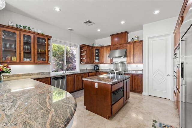 kitchen featuring visible vents, an island with sink, stainless steel dishwasher, range hood, and dark stone counters