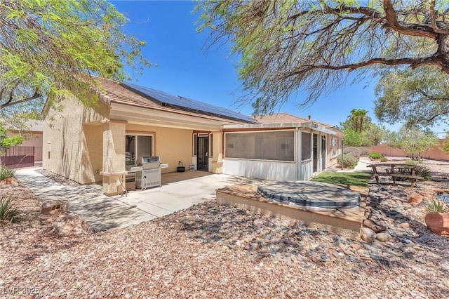 1596 Fieldbrook St, Henderson, NV 89052 - rear view of property with a sunroom, a patio, stucco siding, and solar panels