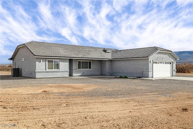 single story home with stucco siding, concrete driveway, a garage, a tile roof, and central air condition unit