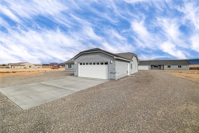 view of side of property featuring concrete driveway, an attached garage, and stucco siding