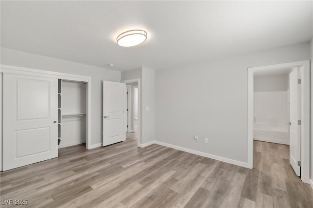 unfurnished bedroom featuring a closet, baseboards, and light wood-style floors