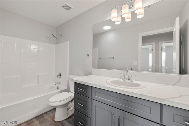 bathroom featuring visible vents, tub / shower combination, toilet, wood finished floors, and vanity