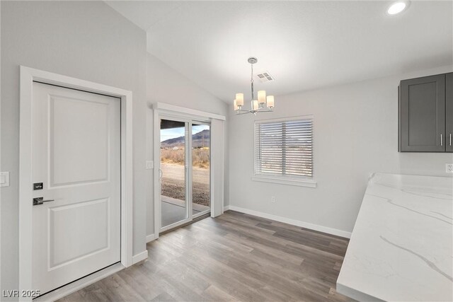 dining space with wood finished floors, baseboards, visible vents, vaulted ceiling, and a chandelier