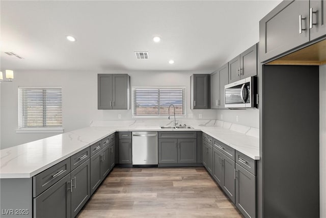 kitchen featuring visible vents, a peninsula, stainless steel appliances, and a sink