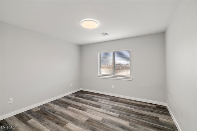 unfurnished room with dark wood-style floors, visible vents, and baseboards