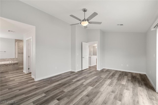 unfurnished bedroom featuring visible vents, baseboards, vaulted ceiling, wood finished floors, and ensuite bath