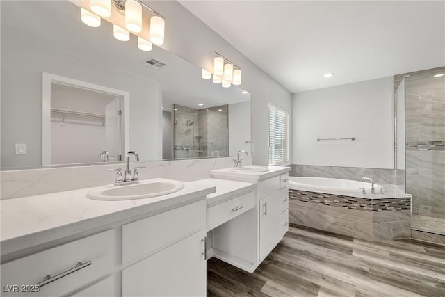 full bathroom featuring visible vents, a garden tub, wood finished floors, a shower stall, and vanity