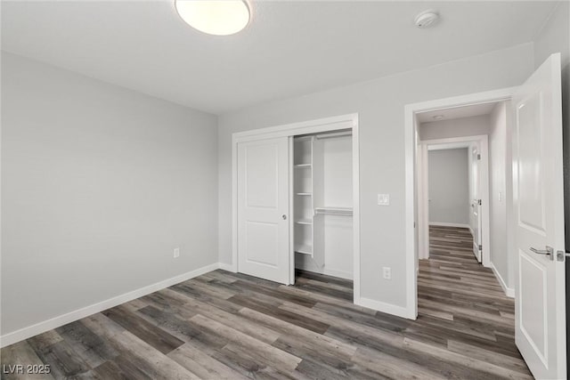 unfurnished bedroom with dark wood-style floors, baseboards, and a closet