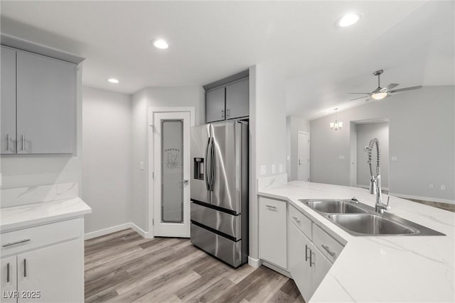 kitchen featuring recessed lighting, stainless steel fridge with ice dispenser, light wood-style floors, and a sink