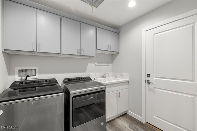 washroom featuring wood finished floors, cabinet space, recessed lighting, a sink, and washing machine and dryer