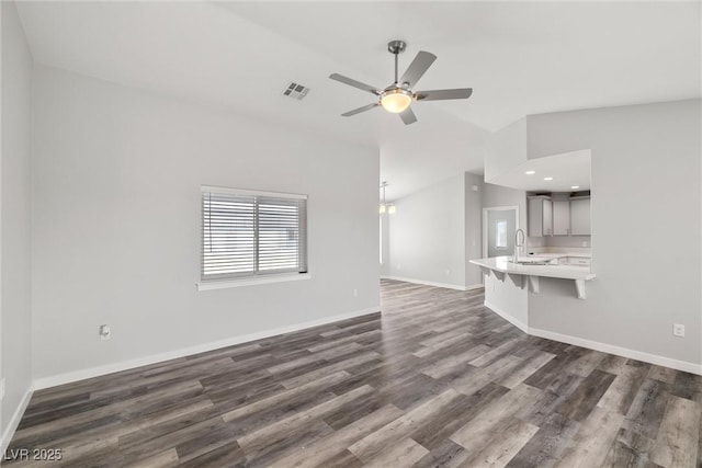 unfurnished living room featuring a sink, baseboards, ceiling fan, and dark wood-style flooring