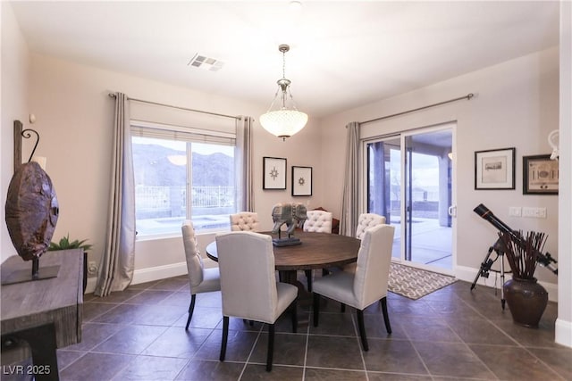 dining space with dark tile patterned floors, a healthy amount of sunlight, visible vents, and baseboards