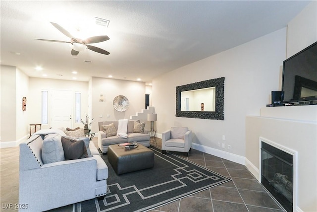 living room featuring recessed lighting, baseboards, a glass covered fireplace, and tile patterned flooring