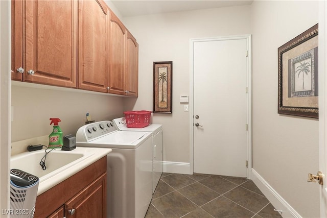 laundry room with dark tile patterned flooring, a sink, cabinet space, baseboards, and washing machine and clothes dryer