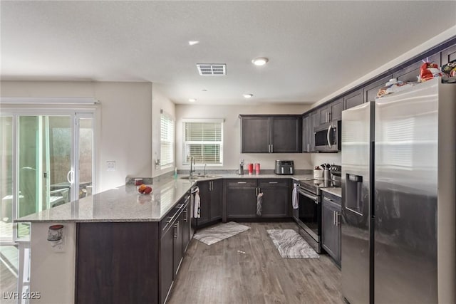 2901 Bahama Yellow Ave, North Las Vegas, NV 89086 - kitchen featuring visible vents, appliances with stainless steel finishes, light wood-style floors, a peninsula, and dark brown cabinetry