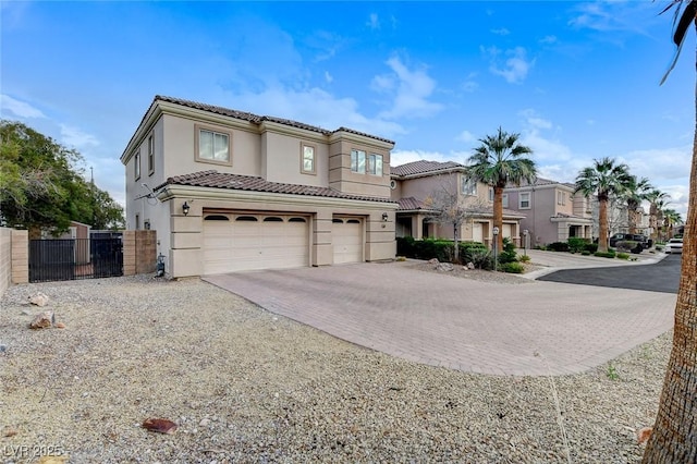 mediterranean / spanish house featuring fence, an attached garage, stucco siding, a tile roof, and decorative driveway