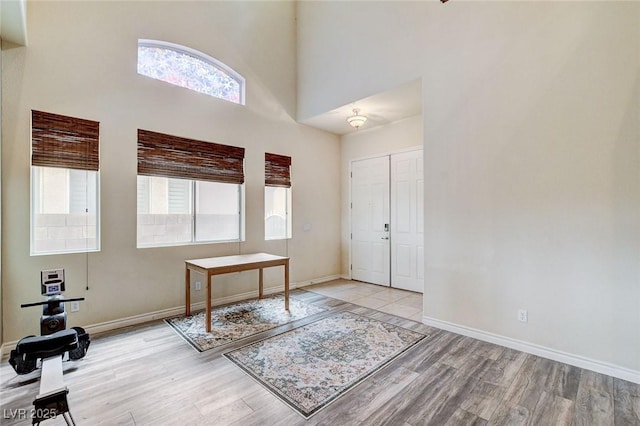 foyer featuring light wood finished floors, a high ceiling, and baseboards