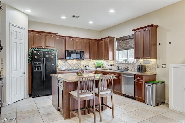 kitchen with visible vents, a center island, light countertops, a kitchen breakfast bar, and black appliances