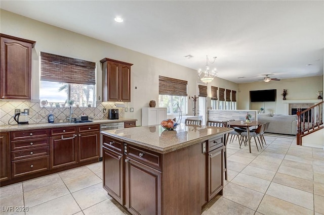 kitchen featuring tasteful backsplash, a kitchen island, light stone countertops, light tile patterned flooring, and plenty of natural light