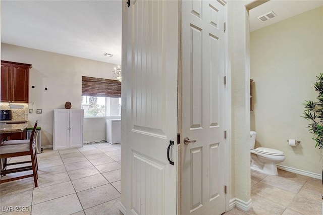 corridor featuring visible vents, baseboards, and light tile patterned flooring