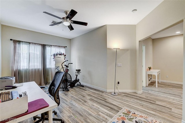 office featuring light wood-style flooring, a ceiling fan, and baseboards