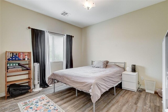 bedroom featuring visible vents, light wood-style flooring, and baseboards