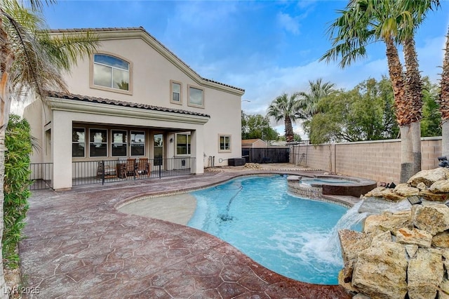 view of swimming pool featuring a fenced backyard, a pool with connected hot tub, and a patio