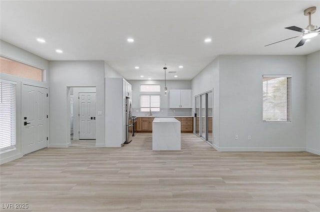 kitchen with open floor plan, light countertops, freestanding refrigerator, and ceiling fan