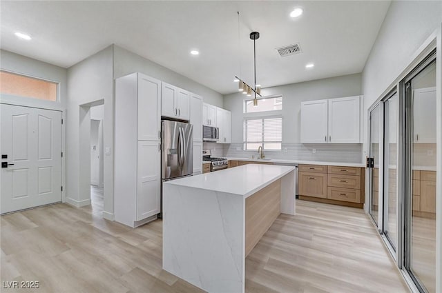 kitchen with visible vents, a sink, backsplash, stainless steel appliances, and light countertops