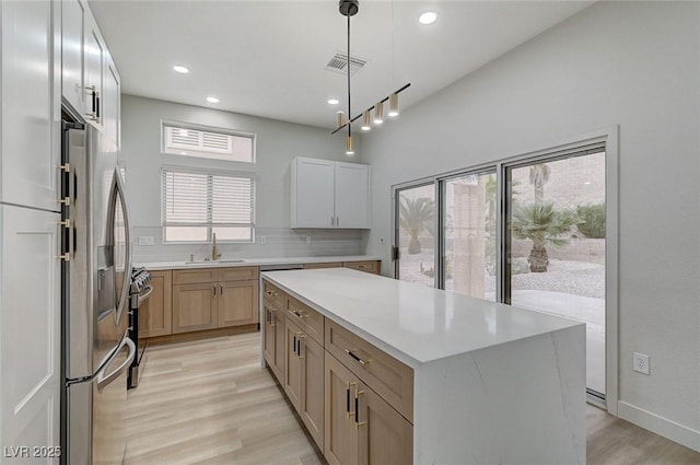 kitchen with visible vents, light wood finished floors, stainless steel appliances, light countertops, and backsplash